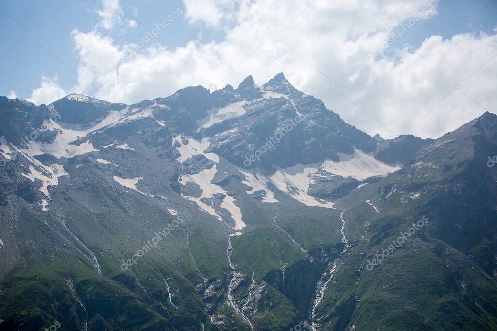 Photo of mountain slopes with vegetation and cloudy sky on summer day