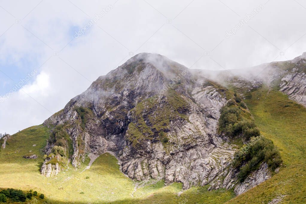 Photo of mountain slopes with vegetation and cloudy sky on summer day