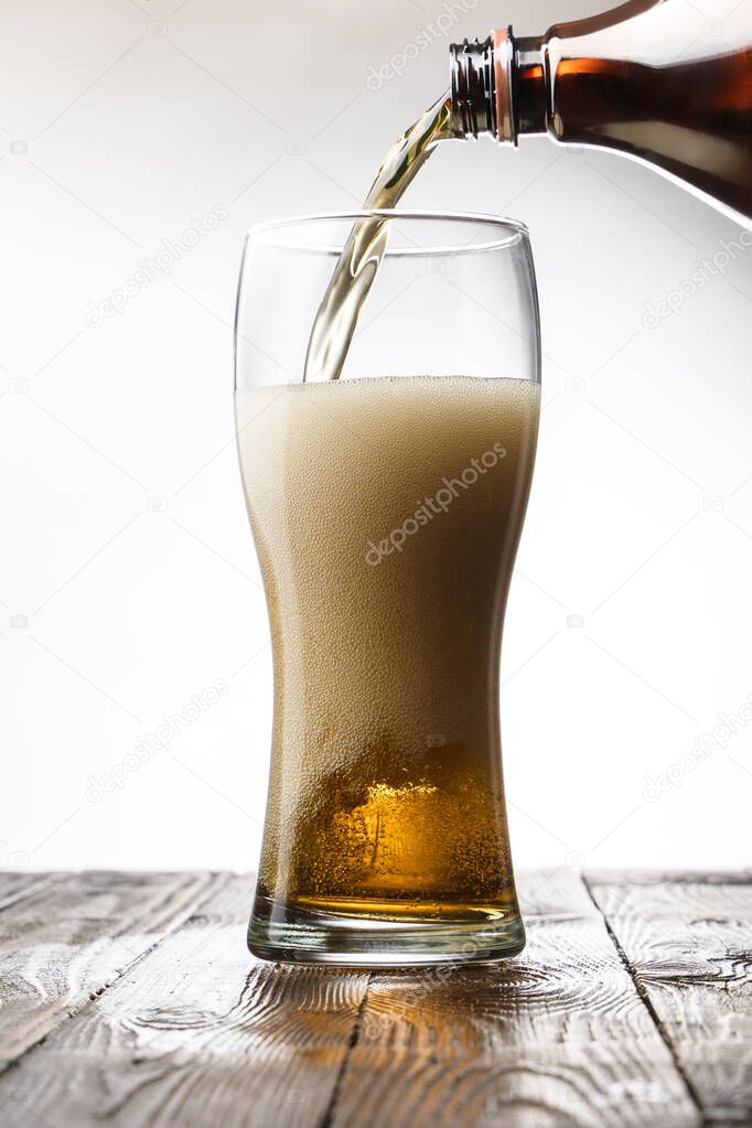 Frosted glass of light beer on wood table and gray background behind