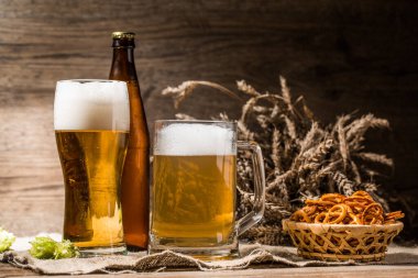 Kupa, bardak, köpüklü bira. Zıpla, kraker ve buğdayla yakın dur.