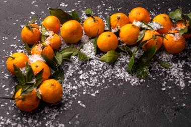 Siyah masadaki karlı mandalinaların fotoğrafını kapat.