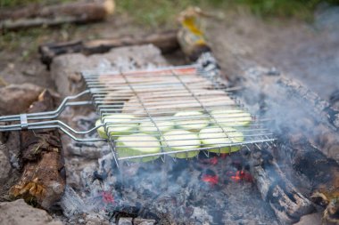 Barbekü için mangal fotoğrafı. Yaz günü ormanda sebzeler ve sosisler yanıyor.