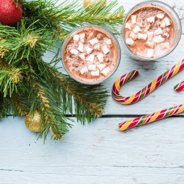 İki bardak marşmelovlu kakao ve beyaz ahşap arka planda oyuncakları olan Noel ağacı. Yukarıdan görüntüle