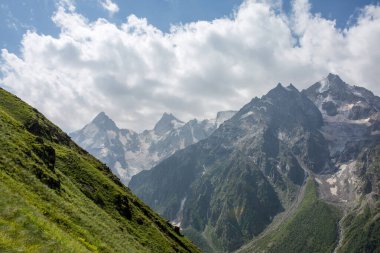 Bitkilerle kaplı dağ yamaçları, yaz günü bulutlu gökyüzü.