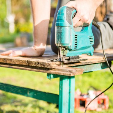 Parkta elektrikli testerelerle tahta kesen adam.