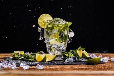 Buzlu bardak, kireç, ahşap masada nane.