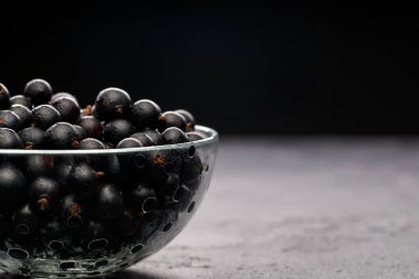 Cam şeffaf fincanda siyah kuşüzümü fotoğrafı. Siyah boş arkaplanda.