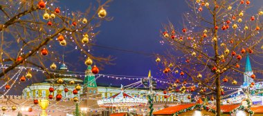 Arkaplanda yanan çelenk ve Kremlin kuleleri olan binaların altın ve kırmızı topları olan ağaç görüntüsü