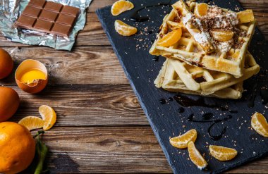 Belçika waffleları, mandalinası, çikolatalı ahşap masa.