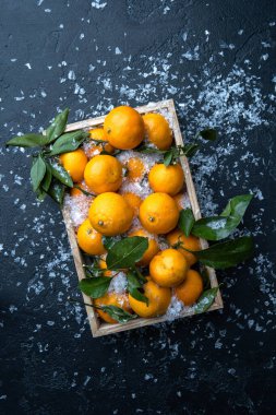 Mandalina resmi, ahşap kutuda, siyah masada, karlı.