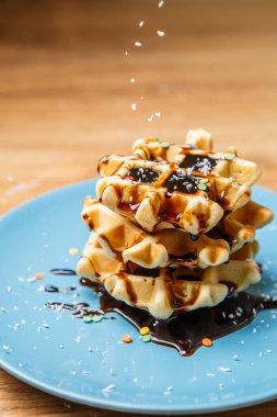 Ev yapımı waffle Çikolata ve hindistan cevizini mavi tabağa serpiyor