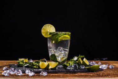Bir bardak mojito, limonlu, ahşap masada nane şekeri.