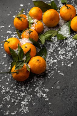 Siyah masadaki karlı mandalinaların fotoğrafını kapat.