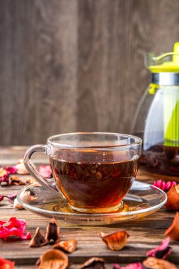 Gül yapraklı masa dekorasyonu ve bir fincan siyah çay.
