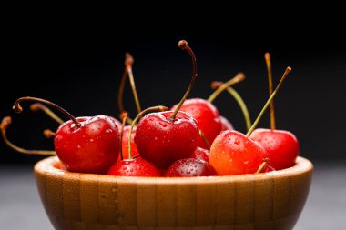 Gri masadaki ahşap bardakta tatlı vişne resmi.