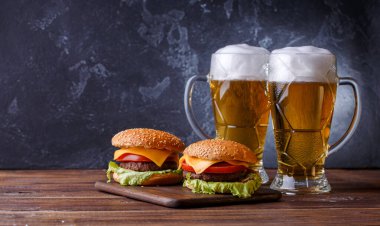 İki hamburger fotoğrafı, ahşap masada biralı bardaklar.