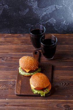 Tahtada iki taze hamburger ve iki bardak meyve suyu resmi.