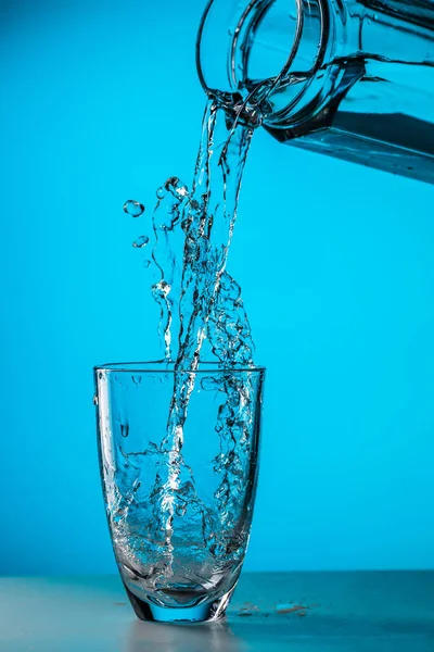 Homem Derrama Água Vidro Vidro Sobre Fundo Azul Estúdio — Fotografia de Stock