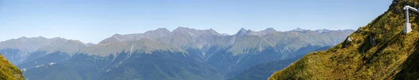 Panoramic photo of mountain landscape in summer against blue sky in afternoon