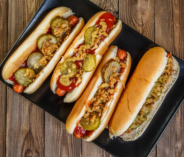 American hot dog with pickles,onions, ketchup and mustard on wood background