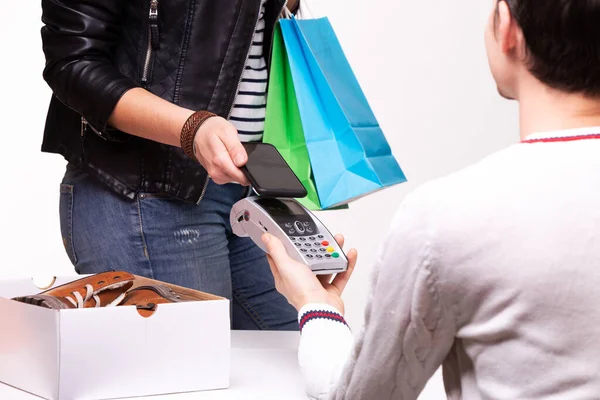 女性のお店のチェックアウト時に靴を購入し 彼女は電話を使用して支払っている ショッピングと小売のコンセプト — ストック写真