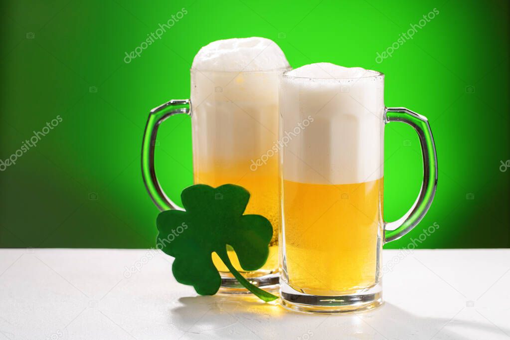 Two mugs of beer on white table. Concept for St. Patrick's day.