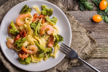 Ahşap zemin üzerinde karides ve brokolili makarna. Düz yatıyordu.