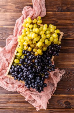 Stüdyoda masasında pembe bez olan tahta kutuda siyah üzüm resmi.