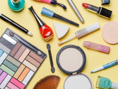 Sarı arka planda farklı kozmetik ürünlerinin üstüne fotoğraf.