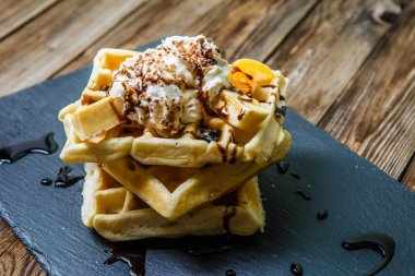 Viyana waffle 'larının fotoğrafı. Çikolata, mandalina ve karatahtanın üstünde dondurma.