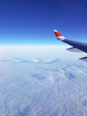 Uçak kanadının resmi, öğleden sonra pencereden bulutlu bir gökyüzü.