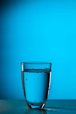 Boş mavi zemin üzerinde su olan cam fotoğraf