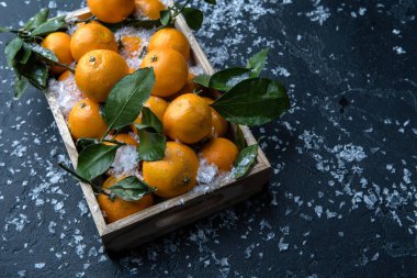 Mandalina resmi, ahşap kutuda, siyah masada, karlı.
