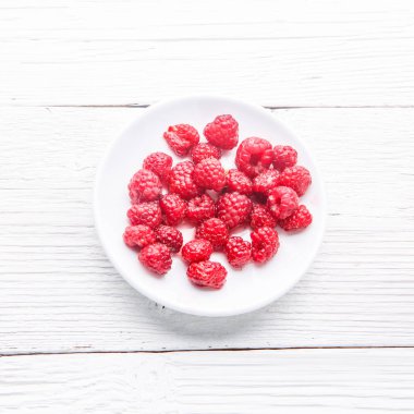 Beyaz ahşap masada ahududu tabağı. Üst görünüm.