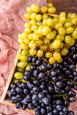 Stüdyoda masasında pembe bez olan tahta kutuda siyah üzüm resmi