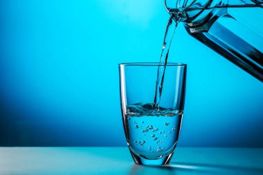 Stüdyonun mavi arka planına camdan cama su döker.