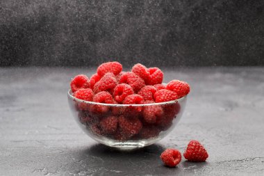 Siyah arkaplanlı şeffaf bardakta ahududu fotoğrafı.