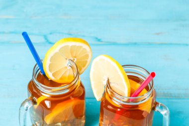 Mavi ahşap arka planda limonlu cam bir kavanozda buzlu çay..