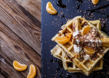 Viyana waffle 'ı, mandalinası, çikolatası olan siyah tahta.