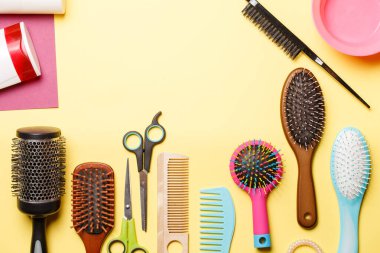 Sarı arka planda izole edilmiş tarak ve makas resmi. Metin için yer