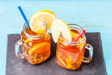 Iced tea in a glass jar with lemon on blue wooden background. clipart