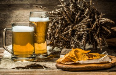 Bardakta bira, içinde buğday filizi olan bardak, gemide patates cipsi.