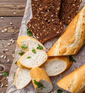 Masanın üzerinde tohum ve otlarla birlikte siyah beyaz ekmek resmi