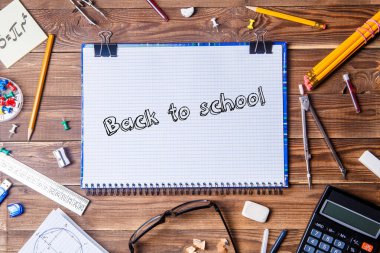 Yazılı bir defter, okula dönüş ve ahşap masa üzerinde öğrenci materyali. Üst görünüm