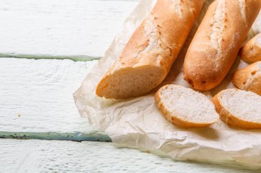 Beyaz ahşap masada kağıt üzerinde taze uzun somun.