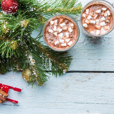 İki bardak marşmelovlu kakao ve beyaz ahşap arka planda oyuncakları olan Noel ağacı. Yukarıdan görüntüle