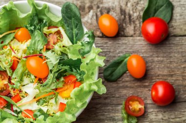 Taze sebze - domates, havuç, biber ve karışık yeşillik - roka salata, mesclun mache - ahşap arka plan üzerinde.