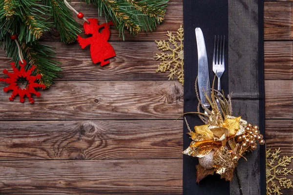 圣诞桌上摆满了用叉子和刀叉装饰的黑色餐巾 金花雪片和圣诞松树枝条 圣诞节背景 — 图库照片