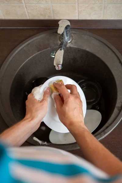 图片来自上面的人的手洗盘子在厨房的水槽里 — 图库照片