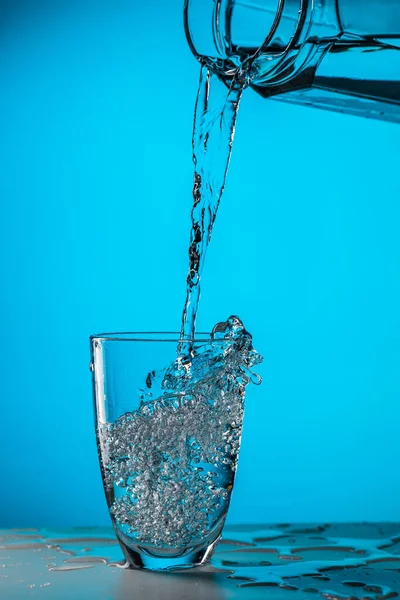 Человек Наливает Воду Стекла Стекло Голубом Фоне Студии — стоковое фото